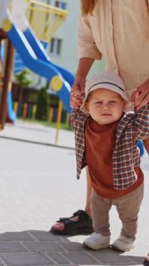 Bir bebek annesinin elini tutarak yürümeyi öğrenir. Çocuk gelişimi. Bebek ilk adımları.