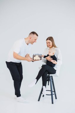 Mutlu bir aile çifti, kucağında küçük bir oğlu ve beyaz arka planda tatlı bir pastası var. Beyaz bir geçmişi olan genç bir aile..