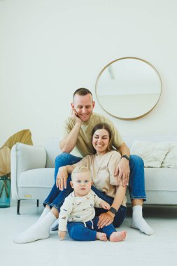 Genç ebeveynler 10 aylık oğullarıyla oynuyorlar. Annem ve babam evde bebekleriyle oynuyorlar. Ebeveynler çocuğa yürümeyi öğretir..