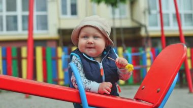 10 aylık bir erkek bebek sokakta durur ve bir desteğe tutunur, çocuk ayakta durmayı öğrenir. Bir çocuğun ilk adımları. Çocuğun kişisel gelişimi. Bebek kıyafetleri.