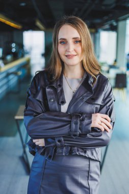 Bir kafede yüzünde gülümseme olan deri ceketli bir kadın..