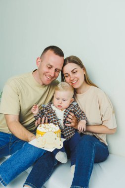 Mutlu ebeveynler küçük oğullarını kollarında tutarlar. Kollarında bir bebekle beyaz bir geçmişleri olan bir aile..