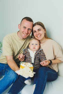 Mutlu ebeveynler küçük oğullarını kollarında tutarlar. Kollarında bir bebekle beyaz bir geçmişleri olan bir aile..