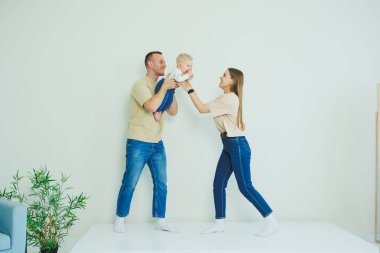 Genç bir aile yeni doğmuş bir bebeği öpüyor ve oynuyor. Ve gülümsüyor. Sevgi dolu bir aile, oğullarını kollarında tutuyor. Mutlu anne, baba ve oğulları.