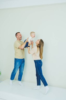Genç bir aile yeni doğmuş bir bebeği öpüyor ve oynuyor. Ve gülümsüyor. Sevgi dolu bir aile, oğullarını kollarında tutuyor. Mutlu anne, baba ve oğulları.