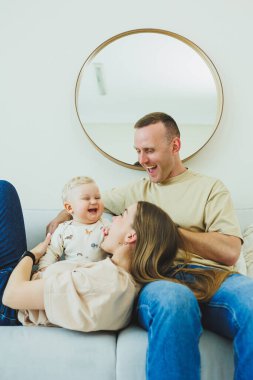 Mutlu ebeveynler küçük oğullarını kucaklıyor ve kucaklıyor. Anne ve baba ve küçük oğlu evde..