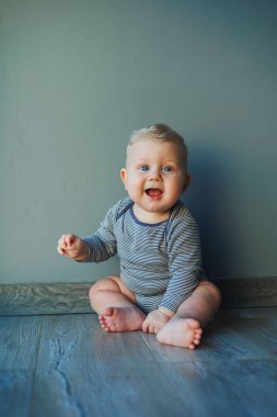 Yüzünde bir gülümseme olan pamuklu bir elbise içindeki küçük bir çocuğun portresi. Gülümseyen mavi gözlü bir bebeğin yüzü.
