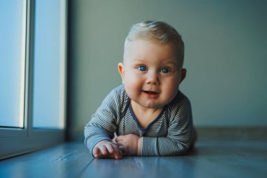 Yüzünde bir gülümseme olan pamuklu bir elbise içindeki küçük bir çocuğun portresi. Gülümseyen mavi gözlü bir bebeğin yüzü.