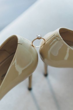 Beyaz topuklu ayakkabı ve değerli taşlı bir nişan yüzüğü. Gelin aksesuarları.