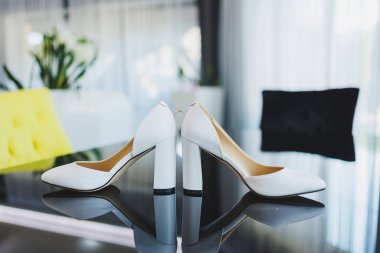 Gelinin aksesuarları. Gelin için düğün ayakkabıları. Alyansların yanındaki yüksek topuklu ayakkabılar, düğün mücevherleri..