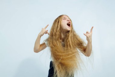 Beyaz tişörtlü ve kot pantolonlu kız portresi beyaz arka planda izole edilmiş. Çocukların duyguları, çocukluk kavramı..