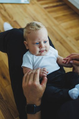 İki aylık bir bebeğin, ailesinin elinde yakın plan çekimleri. Beyaz saçlı, mavi gözlü bir bebek..