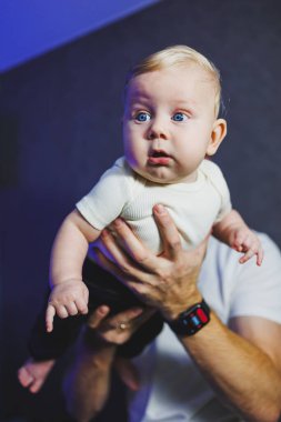 Happy smiling dad is playing with his newborn son. Baby in dad's hands. Smiling child. clipart