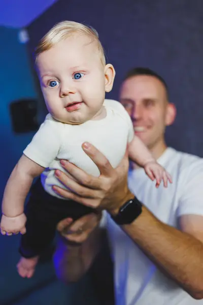 stock image Happy smiling dad is playing with his newborn son. Baby in dad's hands. Smiling child.