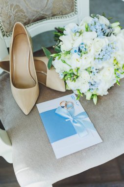 Gelinin aksesuarları. Gelin için düğün ayakkabıları. Alyansların yanındaki yüksek topuklu ayakkabılar, düğün mücevherleri..