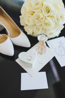 Gelinin aksesuarları. Gelin için düğün ayakkabıları. Alyansların yanındaki yüksek topuklu ayakkabılar, düğün mücevherleri..
