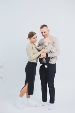 Çocuklu mutlu bir aile çifti. Genç aile babası ve küçük bebek beyaz soyutlanmış arka planda gülümsüyor, evli ve çocuklu bir çift..