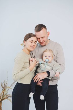 Çocuklu mutlu bir aile çifti. Genç aile babası ve küçük bebek beyaz soyutlanmış arka planda gülümsüyor, evli ve çocuklu bir çift..