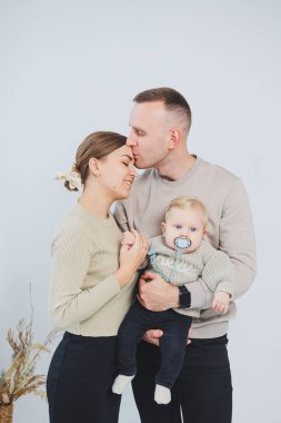 Çocuklu mutlu bir aile çifti. Genç aile babası ve küçük bebek beyaz soyutlanmış arka planda gülümsüyor, evli ve çocuklu bir çift..