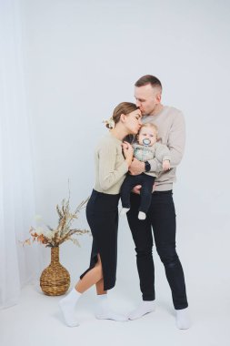 Çocuklu mutlu bir aile çifti. Genç aile babası ve küçük bebek beyaz soyutlanmış arka planda gülümsüyor, evli ve çocuklu bir çift..