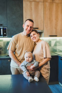 Mutfakta küçük bir oğlu olan genç evli bir çift. Aileler oğullarına sarılırlar..