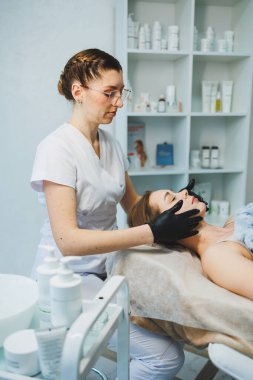 Bir kadın güzellik uzmanıyla randevusunda uzanıyor. Yüz bakımı. Yüz maskesi.