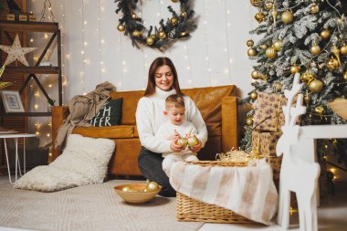 Anne ve oğlu Noel ağacını yeni yıl için süsler. Aile çevresindeki Noel ağacı. Oda yeni yıl için dekore edildi.