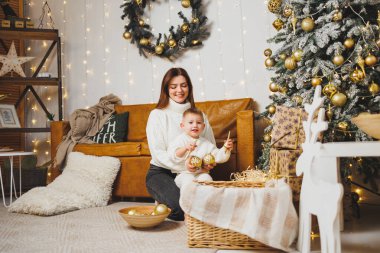 Anne ve oğlu Noel ağacını yeni yıl için süsler. Aile çevresindeki Noel ağacı. Oda yeni yıl için dekore edildi.