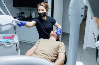 Modern diş aletleri. Ortodontist hastanın dişlerinin üstüne parantez sistemi yerleştiriyor, diş tedavisi. Dişçi sandalyesi.