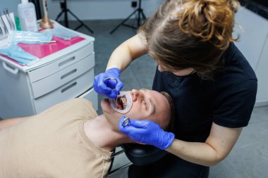 Modern stomatoloji ofisi. Bir ortodontist diş teli takar. Yanlış ısırık almış birinin dişlerini tedavi etmek. Diş tedavisi