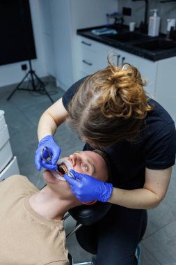 Modern stomatoloji ofisi. Bir ortodontist diş teli takar. Yanlış ısırık almış birinin dişlerini tedavi etmek. Diş tedavisi