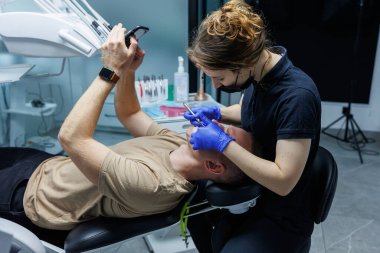 Modern stomatoloji ofisi. Bir ortodontist diş teli takar. Yanlış ısırık almış birinin dişlerini tedavi etmek. Diş tedavisi