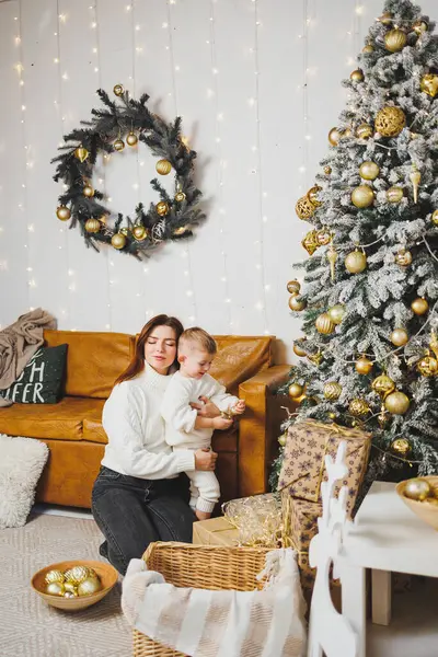 Anne ve oğlu Noel ağacını yeni yıl için süsler. Aile çevresindeki Noel ağacı. Oda yeni yıl için dekore edildi.