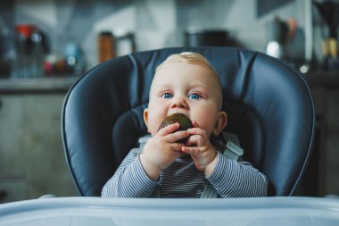 Bir erkek bebek lezzetli bir avokado yer. Bebeğin ilk yemeği. Çocuk bir avokado yiyor.
