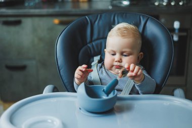 Bebek yüksek bir sandalyeye oturur ve silikon tabaklardan yer. Bebekleri beslemek için araçlar.