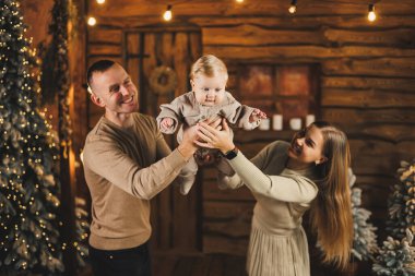 Noel ağacının yanında mutlu bir aile. Genç bir anne ve baba, oğullarını kollarına alıp ona bir şey gösterir. Aile içinde yeni yıl..