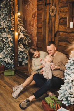 Noel ağacının yanında mutlu bir aile. Genç bir anne ve baba, oğullarını kollarına alıp ona bir şey gösterir. Aile içinde yeni yıl..