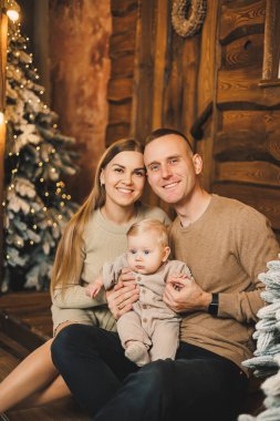 Noel ağacının yanında mutlu bir aile. Genç bir anne ve baba, oğullarını kollarına alıp ona bir şey gösterir. Aile içinde yeni yıl..