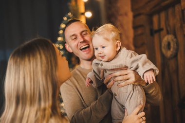 Noel tatillerinin atmosferi. Mutlu bir aile ve küçük bir çocuk, Noel ağacının yanında rahat bir evde yeni yılı kutluyorlar. Aile içinde Noel..