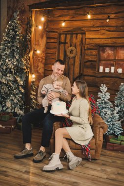 Noel tatillerinin atmosferi. Mutlu bir aile ve küçük bir çocuk, Noel ağacının yanında rahat bir evde yeni yılı kutluyorlar. Aile içinde Noel..