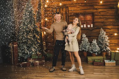 Genç bir anne ve baba Noel ağacının yanında küçük bir çocukla duruyorlar. Yeni yıl aile tatili.