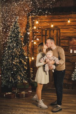 Noel ağacının arkasında çocuklu bir aile. Yeni yıl evinde ellerinde çocuğu olan genç bir adam ve bir kadın. Yeni yılı aile çemberinde kutluyoruz..