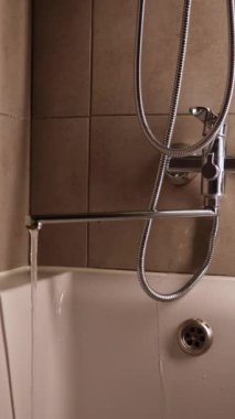 Gümüş su musluğu. Banyodaki musluktan su akıyor. Banyo musluğu. Paslı su musluğu.