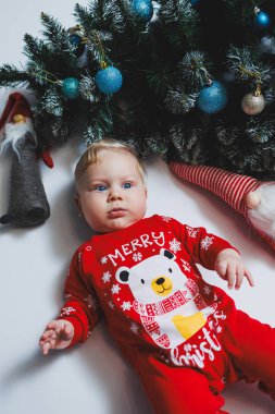 Bebek, Noel ağacının yanında yatıyor. Çocukların ilk Noel 'i. Küçük bir çocuk Noel 'i kutluyor. Yeni yıl tatili. Noel Baba ağacı olan çocuk. Noel Baba bebek.