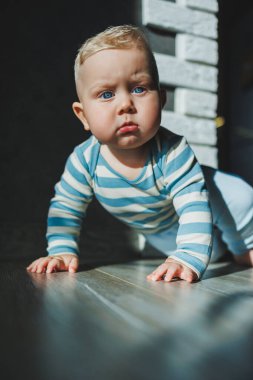 Mutlu gülümseyen çocuk. Gülümseyen yüzüyle yeni doğmuş şirin bir erkek bebek yerde sürünüyor. Annelik bebek bakımı konsepti Mutlu bebek