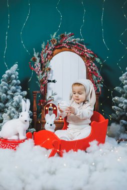 Noel ağacının arka planında tavşan kostümü giymiş küçük bir çocuk. Küçük bir çocuk için Noel kostümü. Yeni Yıl