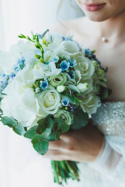 Beyaz elbiseli gelin elinde bir buket taze çiçek tutuyor. Gelinin buketi..
