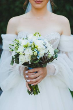 Beyaz elbiseli gelin elinde bir buket taze çiçek tutuyor. Gelinin buketi..