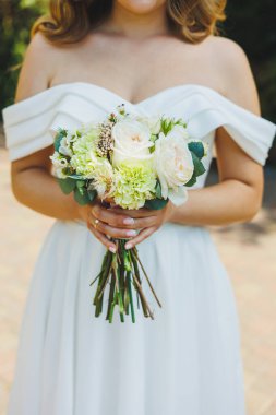 Beyaz elbiseli gelin elinde bir buket taze çiçek tutuyor. Gelinin buketi..