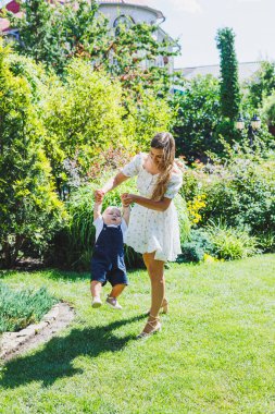 Genç ve mutlu bir anne yürüyüş sırasında bir yaşındaki oğlunu kollarına alır. Sevgi dolu bir anne oğluna sarılır..